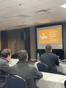 Classroom of three men looking at a giant project screen which says "5 Types" - Self-awareness, Self-regulation, Motivation, Empathy, Social skills